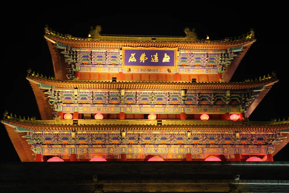 The Drum Tower in Kaifeng lit up at night above the night market